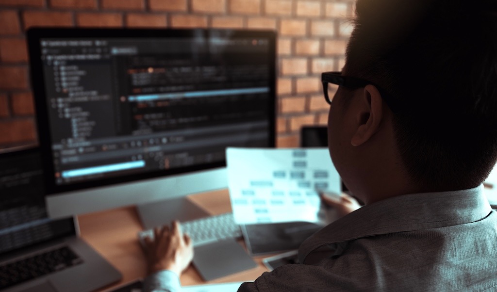 Rear view of the software developer is working on a computer keyboard